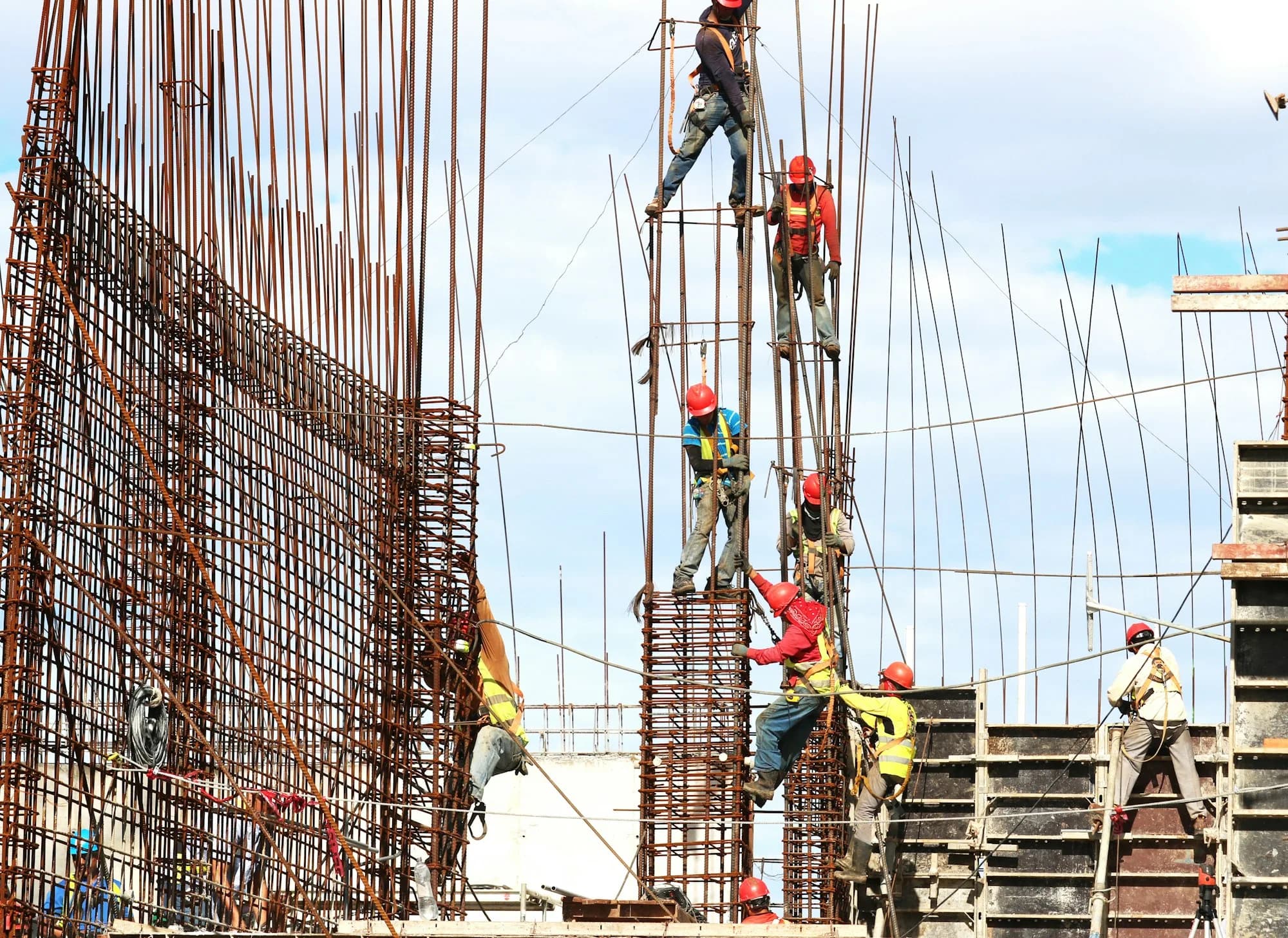 Harnessed crew working reinforcement columns under fall-arrest supervision
